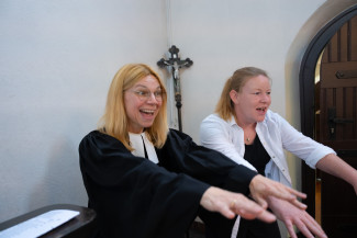 Pfarrerin und junge Frau mit ausgestreckten Händen