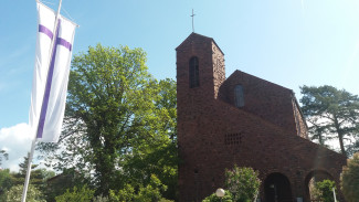 Kreuzkirche Kahl mit Fahne lila Kreuz auf weißem Grund