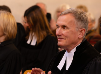 Pfarrer in einer Kirchenbank mit anderen Personen