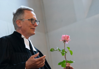 Pfarrer hält Rose in der Hand