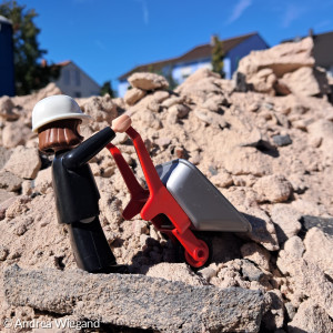 Figut Herr Luther kippt eine kleine Schubkarre auf einem Steinhaufen aus