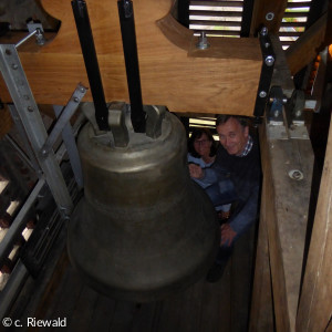 Pfarrer Riewald begutachtet die große Glocke mit neuem Joch