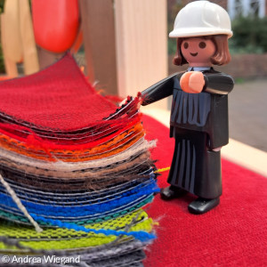 Männchen Herr Luther schaut sich bunte Stoffmuster an
