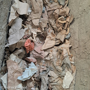 Blick in den gemauerten Altar, der voller Papier und Steine ist