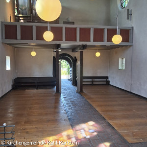 Blick vom Alter der ausgeräumten Kreuzkirche zur Tür mit bunten Farbspiel auf dem Boden durch die Glasfenster